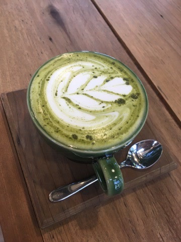 Business First Principles After 15 Years A green matcha drink on a wooden table, illustrating reflection during business building